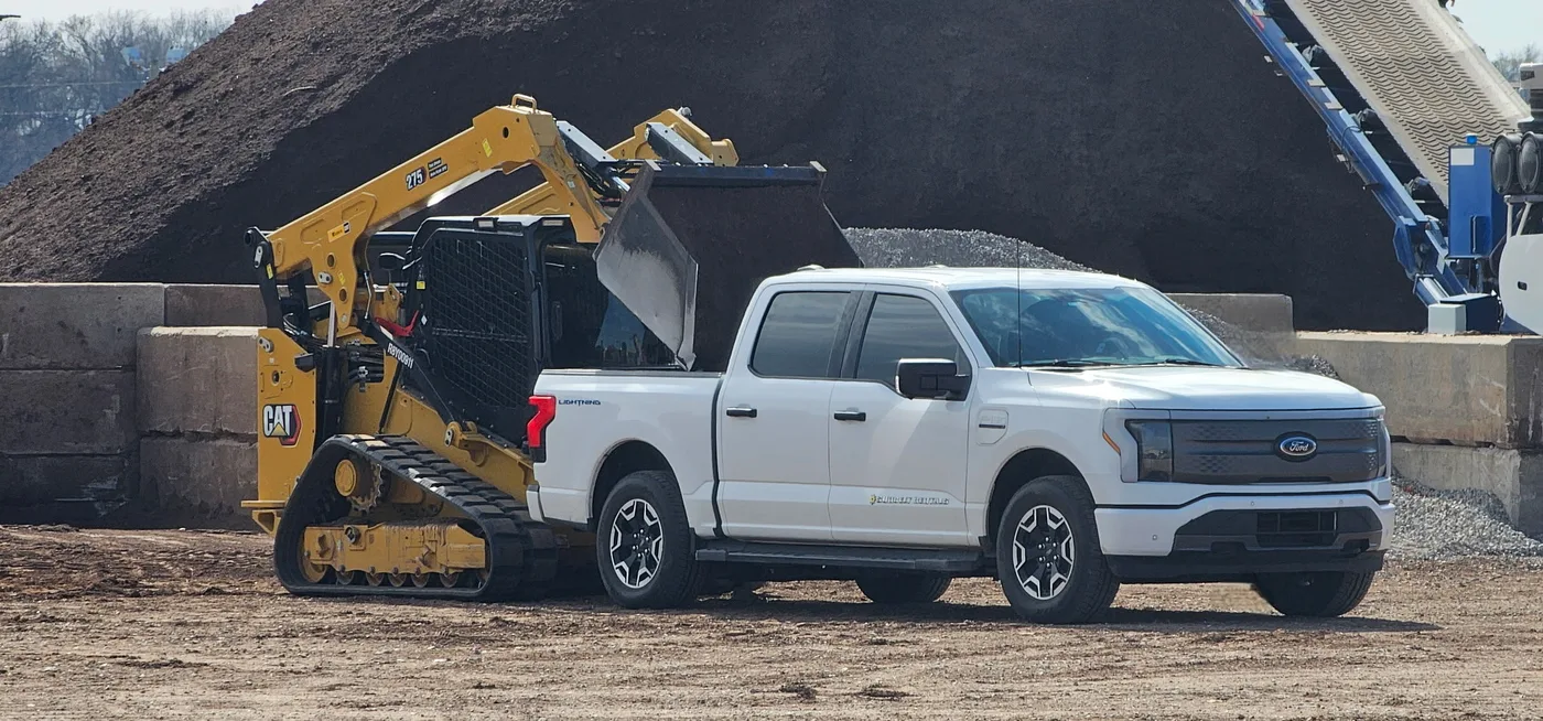 Skid steer loading bulk mulch into a customer's pickup truck at the Riverside Wood yard in Norman, OK